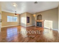 Inviting living room featuring wood floors, a ceiling fan, and a cozy fireplace for comfortable living at 1851 Hillpointe Rd # 2124, Henderson, NV 89074