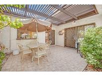 Outdoor patio with tile flooring, patio furniture, umbrella, pergola and small gas grill at 2541 La Cara Ave, Las Vegas, NV 89121