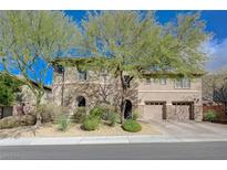 Charming two-story home featuring a combination of stone and stucco exterior, complemented by mature trees and a two-car garage at 2124 Pont National Dr, Henderson, NV 89044