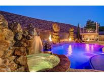 Night view of stunning pool area with rock waterfall, hot tub, and fire features creating an inviting backyard oasis at 2124 Pont National Dr, Henderson, NV 89044