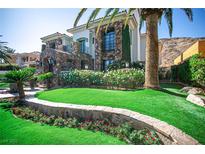 Beautiful two-story home featuring a lush lawn, colorful flowerbeds, and mature palm trees at 2793 Red Arrow Dr, Las Vegas, NV 89135