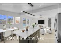 Bright, open-concept living space featuring a kitchen island, dining area and comfortable seating with access to backyard at 2801 Emmons Ave, North Las Vegas, NV 89030