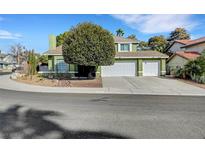 Two-story home featuring a three-car garage, mature tree in the front yard and green paint at 8908 Rocky Shore Dr, Las Vegas, NV 89117