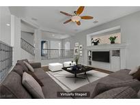 Bright living room with a ceiling fan, neutral colored walls, and sleek white furniture at 11009 Pentland Downs St, Las Vegas, NV 89141