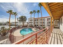 Community pool area with palm trees, adjacent to a multi-story apartment building with a view from the upper floors at 1381 E University Ave # 203, Las Vegas, NV 89119