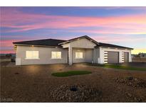 Stunning single-story home featuring a three-car garage and desert landscaping at dusk at 3520 Malibou Ave, Pahrump, NV 89048