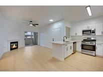 Bright living room features a fireplace, ceiling fan, sliding glass door, and light wood floors at 855 N Stephanie St # 1715, Henderson, NV 89014