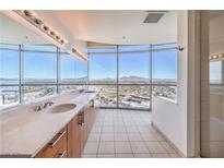 Bright bathroom with dual sinks, a glass shower, and expansive windows offering stunning city views at 200 W Sahara Ave # 2108, Las Vegas, NV 89102