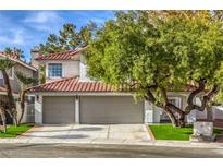 Charming two-story home featuring a tile roof, a two-car garage, and lush landscaping at 2921 Moonlight Bay Ln, Las Vegas, NV 89128