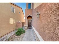 Inviting front entry with a arched entryway, leading to a dark wood front door and landscaped walkway at 7433 Calzado Dr, Las Vegas, NV 89178