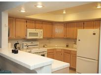 Bright kitchen with light wood cabinets, white countertops, and modern appliances at 7950 W Flamingo Rd # 1139, Las Vegas, NV 89147