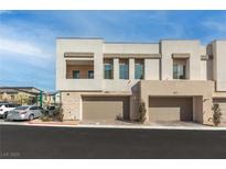 Modern two-story home with a beige facade, two-car garage, balcony, and manicured landscaping at 600 N Carriage Hill Dr # 2098, Las Vegas, NV 89138