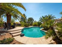 Relaxing backyard oasis with turquoise pool, palm trees, and seating area for enjoying outdoor living at 6557 Secluded Ave, Las Vegas, NV 89110