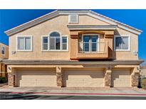 Charming townhouse with three-car garage and tan stucco, enhanced by stone accents and a quaint balcony at 1073 Slate Crossing Ln # 1, Henderson, NV 89002