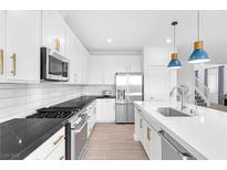 Bright kitchen features white cabinetry, stainless steel appliances, a large island and pendant lighting at 12125 Arrebol Ave, Las Vegas, NV 89138