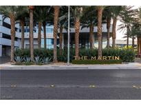 The Martin building entrance with mature palms and manicured landscaping is seen from street level at 4471 Dean Martin Dr # 1105, Las Vegas, NV 89103