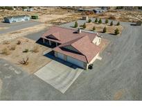 Aerial view of a beige home with a red tile roof, attached garage and extensive desert landscaping at 4681 Melissa Ln, Pahrump, NV 89048