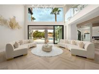 Bright living room featuring curved sofas, herringbone floors and floor-to-ceiling glass doors to the outdoor pool at 74 Innisbrook Ave, Las Vegas, NV 89113