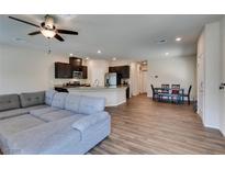 Open-concept living room featuring hardwood floors, a ceiling fan, and a gray couch next to the kitchen at 7450 Pink Moon St # 103, North Las Vegas, NV 89084