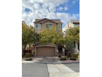 Two-story home with a large garage, manicured landscaping, and a neutral color palette at 10415 Scarpa St, Las Vegas, NV 89178