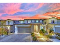 Charming two-story home featuring a brick driveway, attached garage, and well-maintained landscaping at sunset at 12816 Alcores St, Las Vegas, NV 89141