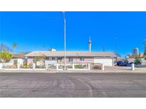 Single story house with white fence, attached garage, desert landscaping, with the Stratosphere in the background at 1805 Ivanhoe Way, Las Vegas, NV 89102