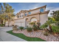 Charming two-story home with desert landscaping, an attached three-car garage and tan stucco at 2107 Eaglepath Cir, Henderson, NV 89074