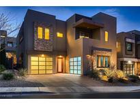 Modern two-story home featuring stone accents and a well-lit driveway, enhancing its curb appeal and contemporary design at 221 Errogie St, Henderson, NV 89012