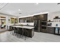 Modern kitchen featuring dark cabinets, stainless steel appliances, and a large center island with bar seating at 8145 Mountain Forest Ct, Las Vegas, NV 89129