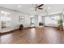 Spacious living room featuring wood floors, ceiling fans, and a stone fireplace at 8212 Ducharme Ave, Las Vegas, NV 89145