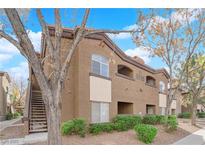 Condo exterior with brown stucco, tile roof, second story entrances and mature trees at 9000 Las Vegas Blvd # 2138, Las Vegas, NV 89123