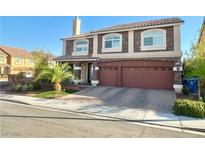 Two-story home featuring a two-car garage, landscaped yard, and a combination of stone and stucco facade at 6205 Windy Oaks Ct, Las Vegas, NV 89139