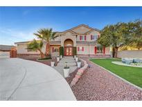 Charming home featuring a landscaped front yard, a long driveway, and an arched entrance with red double doors at 7771 Pleasant Slopes Ct, Las Vegas, NV 89131