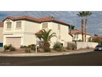 Beige two-story home featuring a red tile roof, desert landscaping, and a two-car garage at 10228 W Crepe Myrtle Ct, Las Vegas, NV 89183