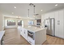 Open-concept kitchen boasts white cabinets, stainless steel appliances, and a large island with a built-in microwave at 2581 Terrytown Ave, Henderson, NV 89052