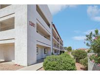 Apartment building featuring multiple stories and balconies, with lush greenery in front and blue skies overhead at 1381 E University Ave # 301, Las Vegas, NV 89119