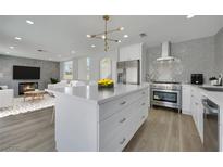 Modern kitchen with stainless steel appliances, a large island, and an open view to the living room with fireplace at 1620 Western Lily St, Las Vegas, NV 89128