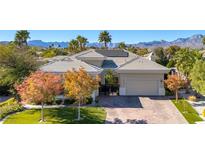 Charming single-story home with lush landscaping, a brick driveway, and mountain views in the background at 605 Hermosa Canyon Dr, Las Vegas, NV 89145