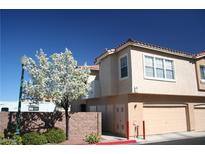 Two story tan condo featuring a two car garage, blooming tree, and red roof at 102 Harbor View Dr # 102, Boulder City, NV 89005