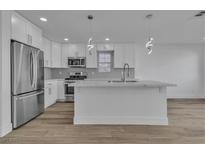 Modern kitchen featuring white cabinets, stainless steel appliances, gray backsplash, and an island at 7640 Sea Wind Dr, Las Vegas, NV 89128