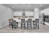 Bright kitchen features white cabinets, stainless steel appliances, large island with chairs, and wood-look tile flooring at 351 Dandelion Brook Ct Ct, Las Vegas, NV 89148