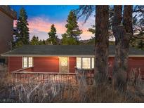Charming exterior featuring a cozy front porch and mature trees under a colorful sunset at 4154 Matterhorn Way, Mount Charleston, NV 89124