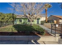 Charming green home featuring a well-maintained lawn and black wrought iron fence at 525 Date St, Boulder City, NV 89005