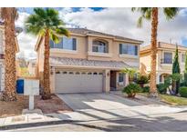 Two-story home featuring a two-car garage, desert landscaping, and mature palm trees at 865 Eureka Falls Ct, Henderson, NV 89052