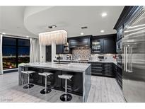 Modern kitchen featuring a large island with seating, stainless steel appliances, and dark cabinetry with accent lighting at 9101 Alta Dr # 1206, Las Vegas, NV 89145