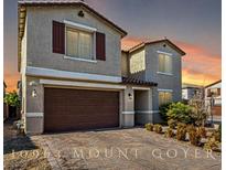 Two-story home featuring a brick driveway, stucco exterior, shutters, and a two-car garage at 10963 Mount Goyer St, Las Vegas, NV 89141