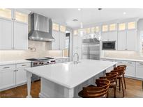 Bright white kitchen with a large island, stainless steel appliances, and stylish pendant lighting at 12169 Castilla Rain Ave, Las Vegas, NV 89138