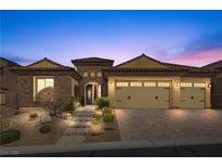 Charming single-story home showcases stone accents, a three-car garage, and desert landscaping with lighted walkway at 2436 Chateau Napoleon Dr, Henderson, NV 89044