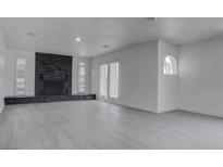 Spacious living room features a striking stone fireplace and ample natural light from large windows and french doors at 501 National St, Henderson, NV 89015