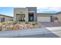 Inviting front exterior with stone accents, desert landscaping, and a brick driveway leading to a two-car garage at 12588 Heritage Heights Dr, Las Vegas, NV 89138